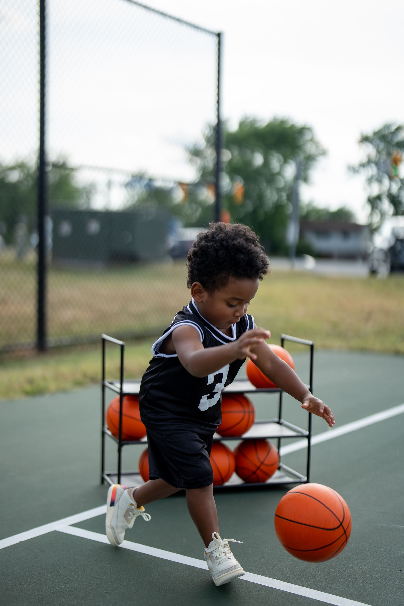 A young basketball player dribbling on an outdoor court