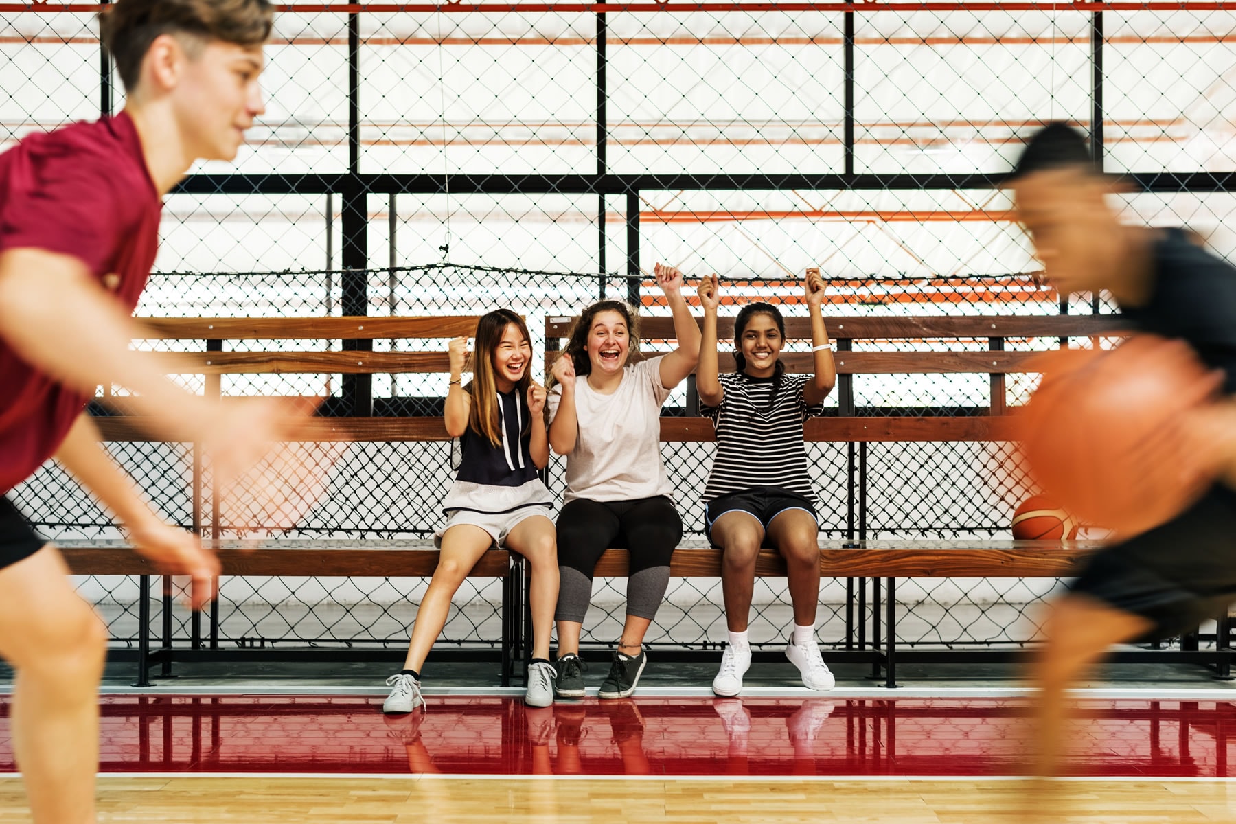 Young athletes cheering courtside during a lively basketball game